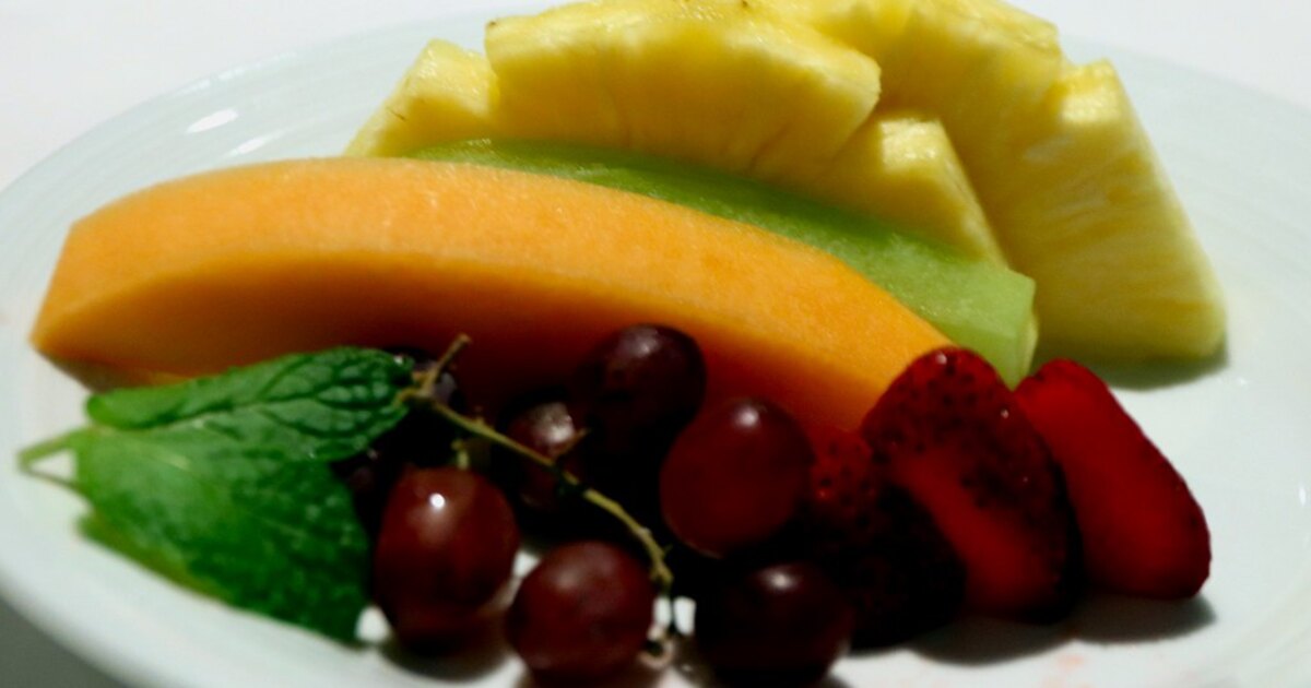 Une tranche de melon orange servie dans une assiette de fruits